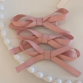 Nahaufnahme von drei rosa Satin-Haarschleifen auf einem weißen Keramiktablett - Rosa