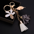 Porte-clés élégant avec fleurs et pompons sur un coffret à bijoux sombre - Gris