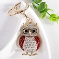 Porte-clés chouette doré avec lunettes noires et cristaux sur une assiette blanche - Rouge