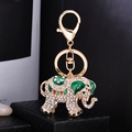 Golden elephant keychain with white rhinestones and green enamel on a black gift box - Green