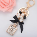 Elegante llavero de perlas con lazo y colgante de frasco de perfume dorado con cristales - Dorado