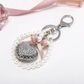 Exquisite rhinestone heart keychain with pearls and a pink silk bow on white background - Silver