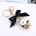 Elegant keychain featuring black satin bow with large pearl and golden crown charm - Angel - Gold