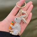 Golden rabbit keychain with white crystals and carrot charm held in hand - AB White
