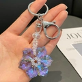 Iridescent purple crystal snowflake keychain with silver lobster clasp on a magazine - Purple