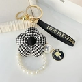 Eleganter Schlüsselanhänger mit Hahnentritt-Blume, weißen Perlen und Gold-Anhänger - Schwarz Hahnentritt