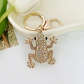 Funkelnder Frosch-Schlüsselanhänger mit Regenbogen-Strass auf einer weißen Platte - Champagner