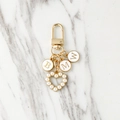 Custom gold metal keychain with pearl heart charm and BMW letter pendants on marble surface - Three Letters Style