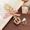 Elegant crown keychain with pink bow, white pearl, and shimmering crystals on gold ring - Pink