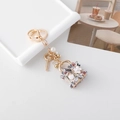 Golden keychain with luxury tweed bag charm, white flower detail, and pearl accents - Grey Red