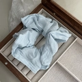 Detail of light blue wrinkled fabric scrunchie displayed in a vintage wooden jewelry box - Blue
