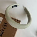 Detail of light green padded headband with handmade label and satin fabric texture - Shiny Green