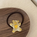 Vista dettagliata di un elastico per capelli a forma di orso su un vassoio di legno - Orso Giallo Cuore Giallo