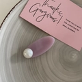 Primer plano de horquilla lavanda con detalle de perla sobre plato de cerámica con textura - Morado