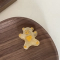 Dettaglio di un fermaglio per capelli a forma di orso in resina ambrata su vassoio - Orso Giallo Trasparente Cuore Giallo