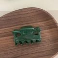 Detail einer glänzenden dunkelgrünen Acetat-Haarklammer auf einem Holztablett mit Feder - Marquise-Kralle / Dunkelgrün