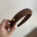 Detalle de diadema acolchada de satén marrón chocolate con placa de metal dorada - Caqui