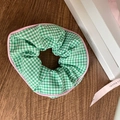 Detailed shot of green gingham scrunchie with pink trim on dark wood tabletop - Green Plaid