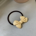 Detail view of a cream-colored bow hair tie with elegant marble texture and elastic band - Creamy Yellow Bowknot