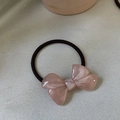 Dettaglio di un elastico rosa con fiocco in acetato, trama marmorea e laccetto nero - Fiocco Rosa