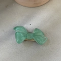 Macro detail of a green marble resin bow hair clip with a gold-tone metal base - Transparent Green