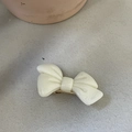 Close-up of cream bow hair clip with marble texture and golden metal spring clip - White