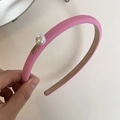 Detail eines rosa Stoffhaarbands mit großer Perle und goldener LOVEDAYS-Plakette - Rosa