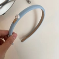 Detail view of a light blue leather headband with large white pearl and gold metal plaque - Blue
