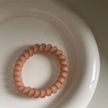 Nahaufnahme eines mattrosa Spiral-Haargummis mit hochelastischem Telefonkabel-Design - Rosa