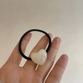 Detail of black elastic hair tie featuring white acrylic heart charm with printed text - Cream White Heart