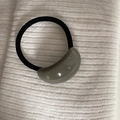 Detalle del accesorio de resina topo en una goma de pelo elástica negra minimalista - Coletero Ovalado Gris
