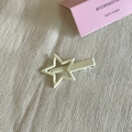 Dettaglio del fermaglio a stella beige crema con finitura opaca e clip a becco d'anatra - Bianco
