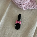 Kreative schwarze Haarspange in Löffelform mit rosa Schleife auf Stoffhintergrund - Schwarz