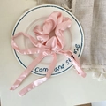 Elegant pink satin scrunchie with long bow ribbon displayed on a white ceramic plate - Pink