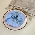 Floral scrunchie in light blue fabric with pink satin trim on a white plate - Pink Edged Blue