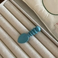 Detailed macro view of a cute blue candy-colored caterpillar hair clip with a smiley face - Blue