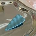 Detailed macro view of the sky blue matte wavy hair clip on a silver display tray - Blue Textured Triangle