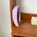 Detail of lavender padded sponge headband with fine fabric texture on a wooden stand - Purple