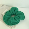 Detailed view of emerald green knitted scrunchie with thick wool texture and soft fabric - Green