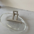 Detail of matte beige cross claw clip on a glass plate showing spring and handle texture - Coffee Bar Hair Claw (7#)
