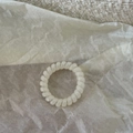 Nahaufnahme weißes Spiralhaargummi mit Perlmuttglanz auf minimalistischem Papierhintergrund - Weiß