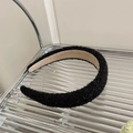 Detail of a thick black fuzzy headband on a tray showing soft texture and brown lining - Headband / Black