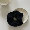 Close-up of black knitted oversized scrunchie texture on a minimalist white ceramic plate - Black