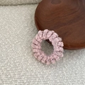Close-up of pink spiral knitted hair tie on a wooden tray with soft fabric texture - Pink Textured