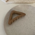 Detalle macro de la pinza de pelo de terciopelo beige sobre un plato de cerámica - Pinza Triangular Té con Leche