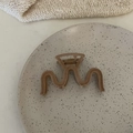 Detalle de textura flocada en pinza de pelo grande marrón ondulada en un plato - Pinza en Forma de M Té con Leche