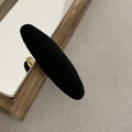 Detail view of a black velvet oval hair clip with a soft sponge padding texture - Black