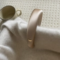 Detail van de goudkleurige gevoerde hoofdband met metalen geloof in jezelf label - koffiekleur