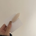 Knitted oval BB hair clip in beige textured finish shown on display card - Off White
