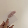 Close-up of pink knitted oval hair clip showing detailed wool weaving texture and design - Pink